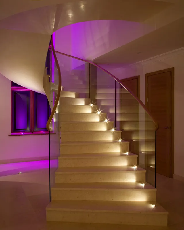 A stone and marble staircase with accent lights shining across each tread in a striking modern house