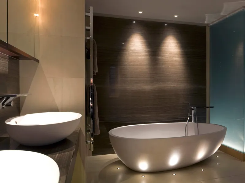 A freestanding bath uplit with small LED accent lights and an uplit frosted glass wall