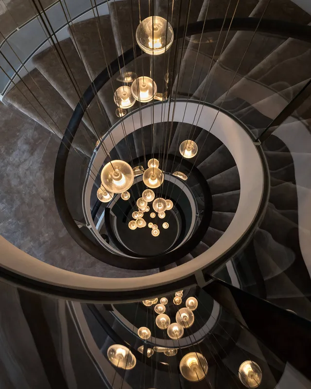 A custom bocci pendant falls through a spectacular spiral staircase spanning four storeys