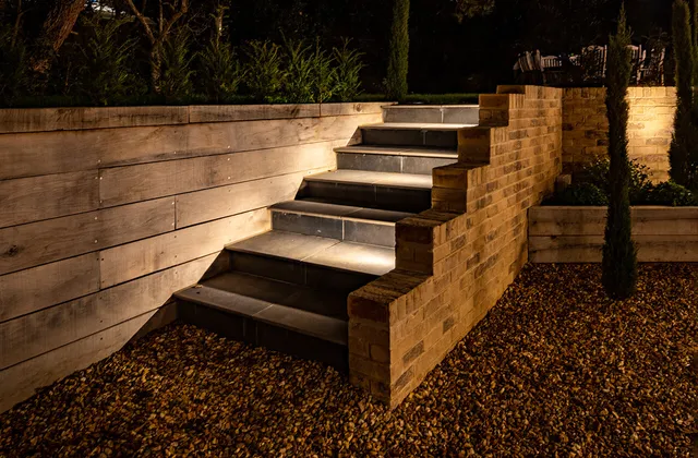 Exterior stone steps with wash of light across the tread from recessed wall lights