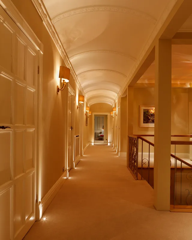 Layers of light illuminate the arched ceiling corridor of a restored Arts and Crafts house