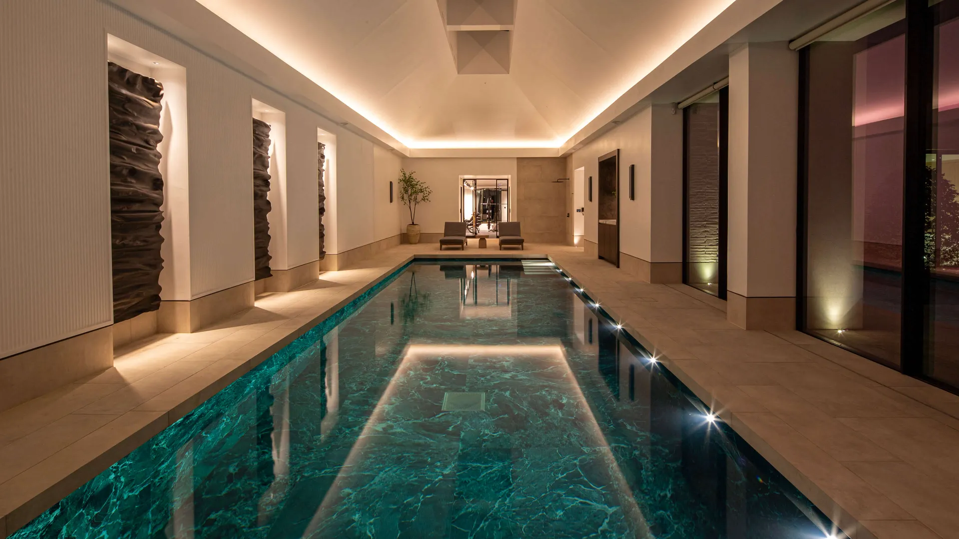 A beautifully tiled swimming pool with coffer lighting in a pitched ceiling