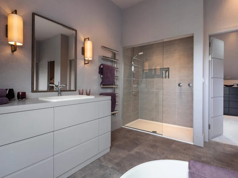 A comfortable modern bathroom with decorative wall lights either side of the mirror