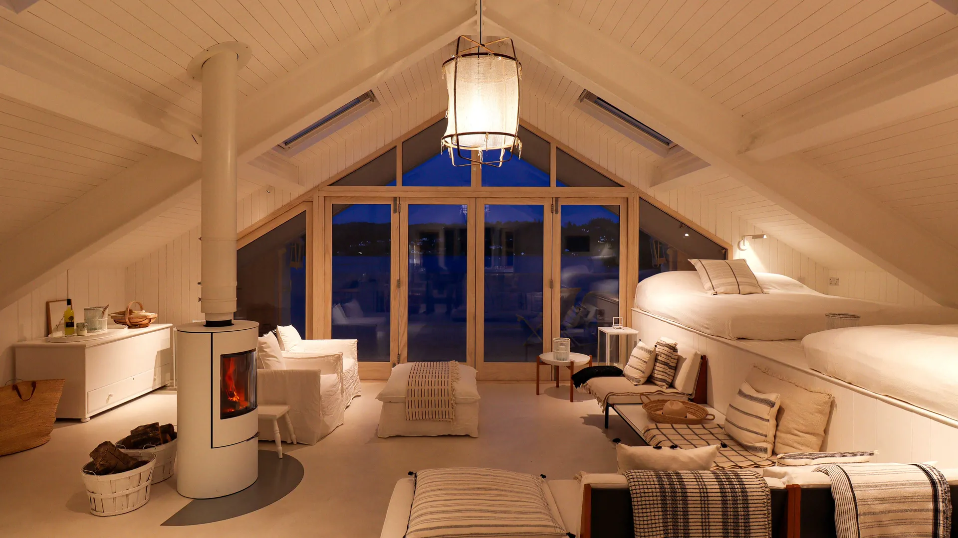 Scandi style boathouse at blue hour with a roaring log-burning stove