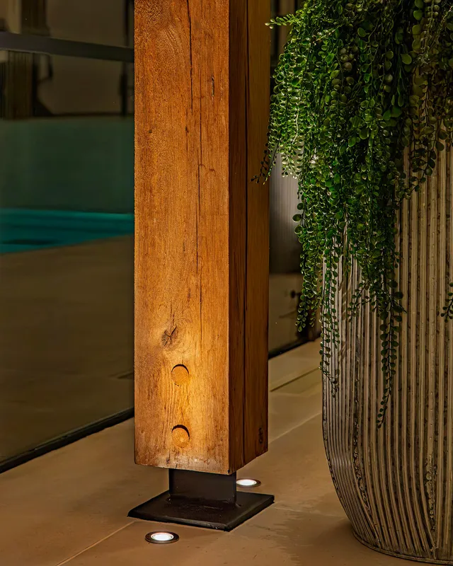A timber beam with ground recessed uplighting in a swimming pool