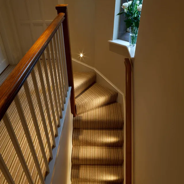 Miniature LED accent lights lighting the staircase treads in a restored Arts and Crafts house 