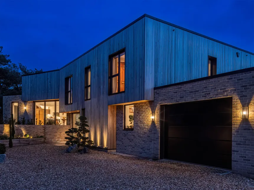 A red cedarwood house in the early evening.  The warm LED lighting brings our the richness of the wood at Blue hour