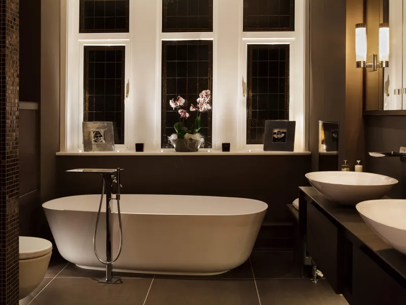 An elegant bathroom with a free-standing bath, mirror lighting and accent uplighting