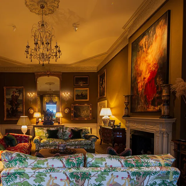 A large painting in a formal drawing room lit with surface mounted spotlights on the ceiling