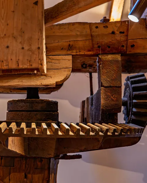 Close up of watermill machinery in a converted mill lit with discreet surface mounted spotlights.