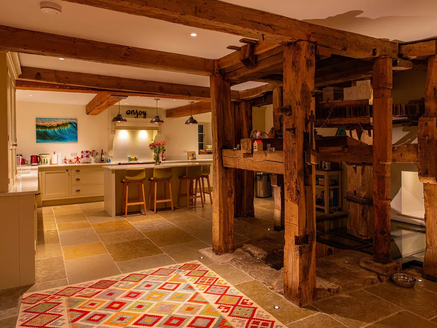 Brightly lit kitchen and beautiful original mill machinery in an old converted watermill.