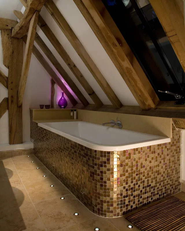 Uplighting around the bath and a splash of colour in a low-ceilinged bathroom