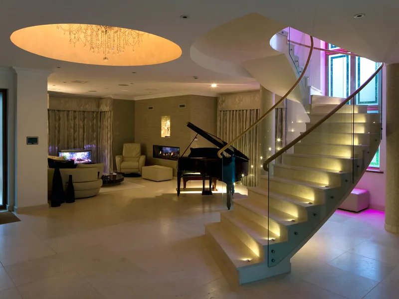 A striking helical marble and concrete staircase with subtle tread accent lighting