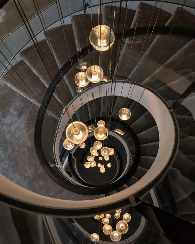 A custom bocci pendant falls through a spectacular spiral staircase spanning four storeys