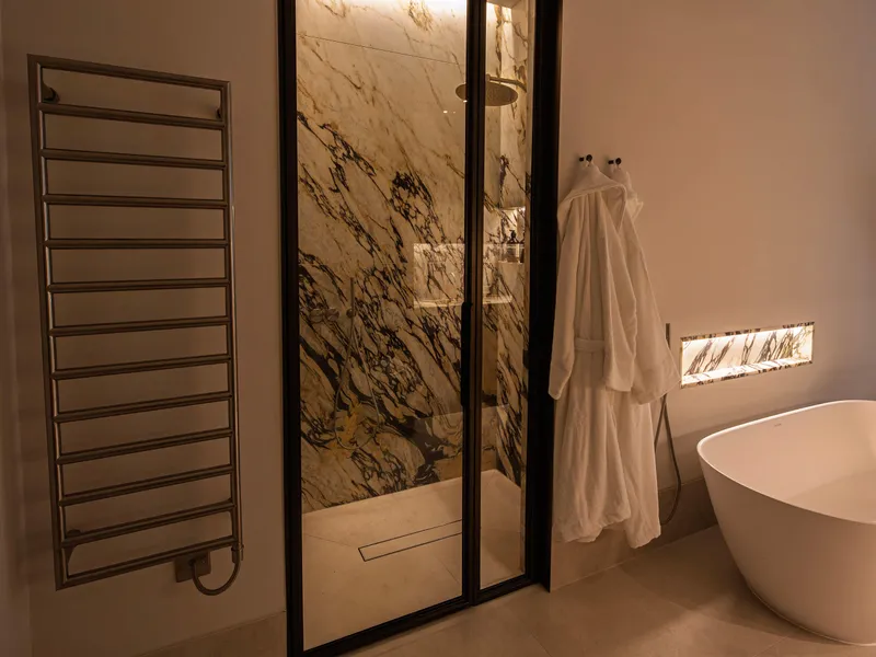 Soft evening lighting in a modern bathroom with lit shower shadow gap and niches