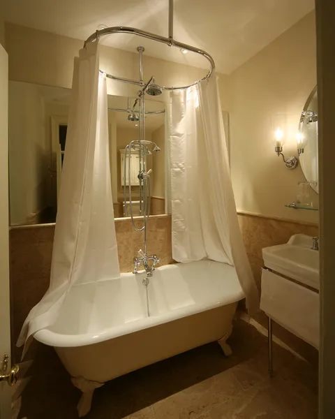 A curtained shower over a free-standing roll-top bath