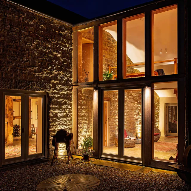 Glazed link at night with lighting outside and inside lighting the stone walls