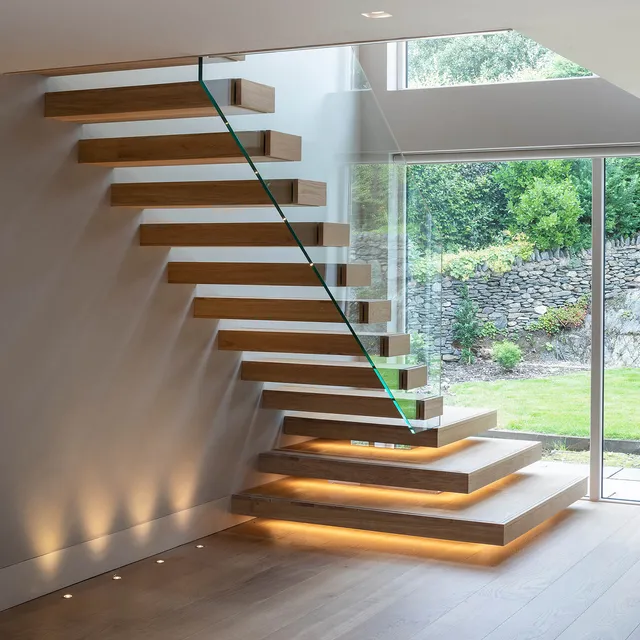 Uplighting and under-tread lighting highlights the cantilevered wooden staircase