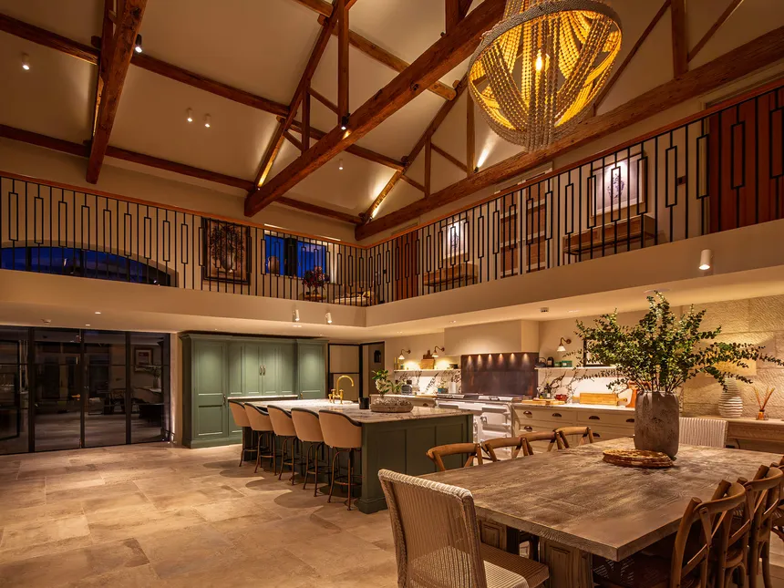 Kitchen in a converted barn with exposed beams and mezzanine floor