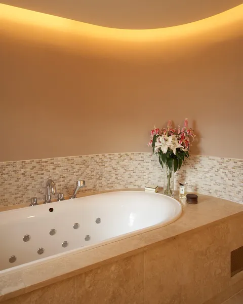 A curved bathroom wall with a lighting cove and a warm white wall wash