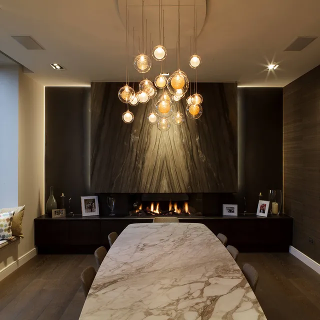 Dining table with custom pendant and a feature granite fireplace with recessed LED linear lighting