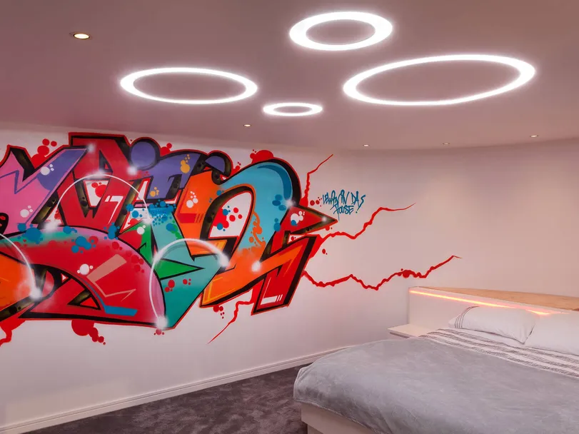 Colour changing LED fittings in a teenager's bedroom with grafiti on the wall