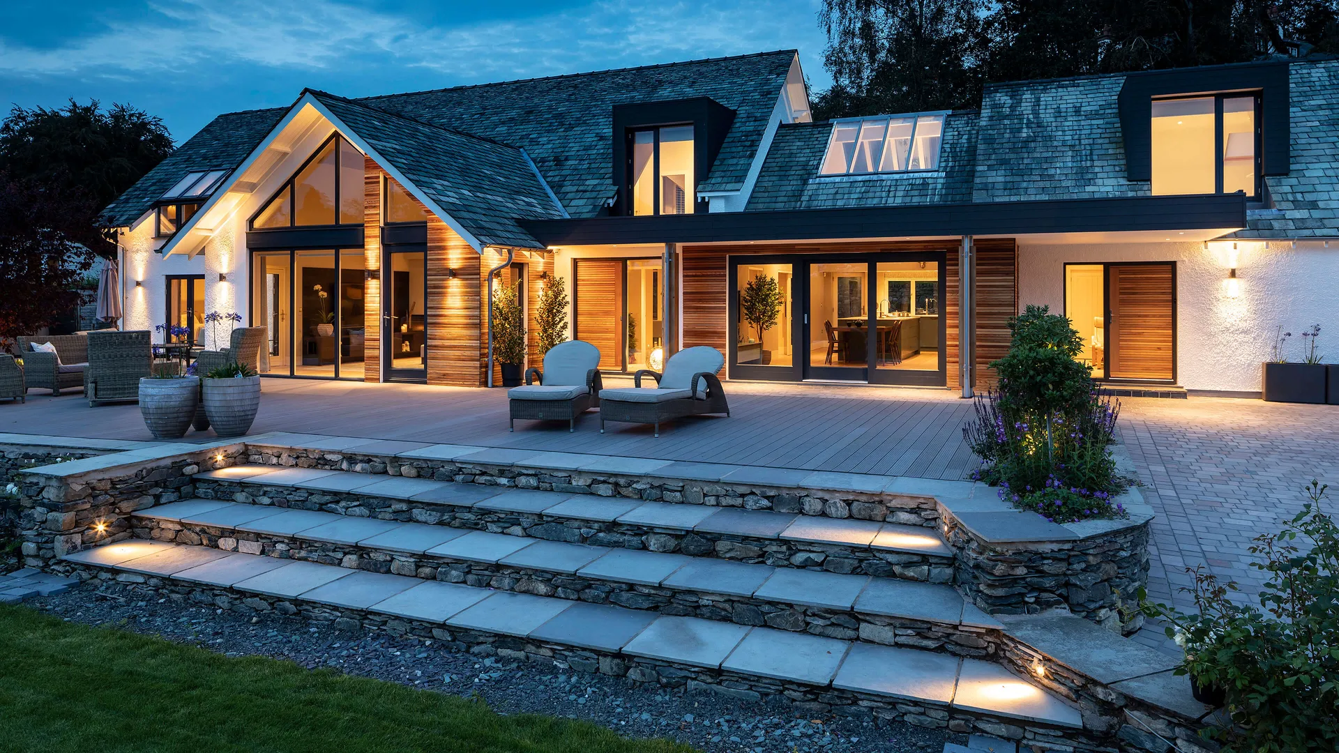 A modern Lakeland house with external lighting and accent lighting leading into the garden