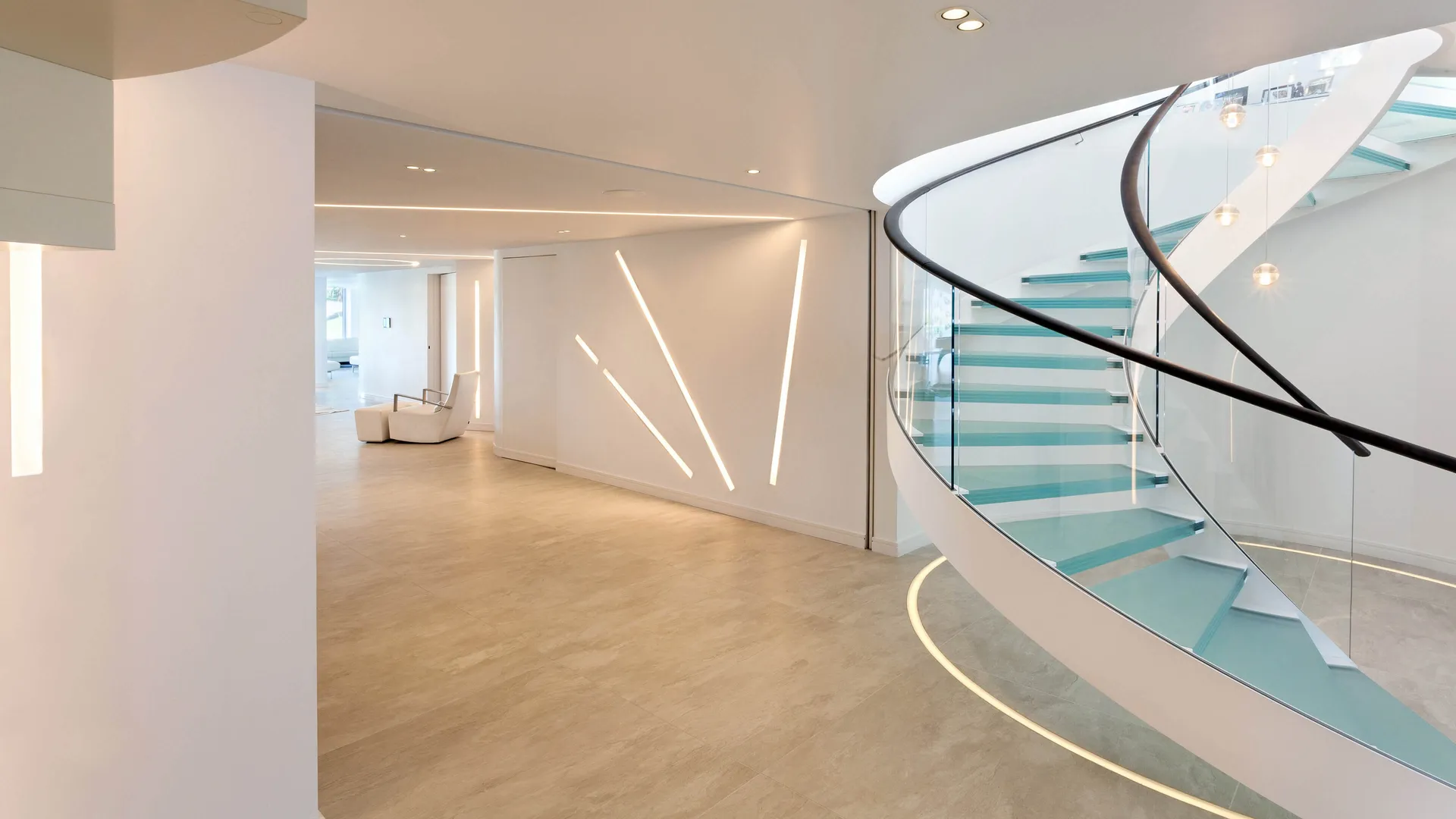 A spiral staircase and basement lit with recessed linear LED lighting