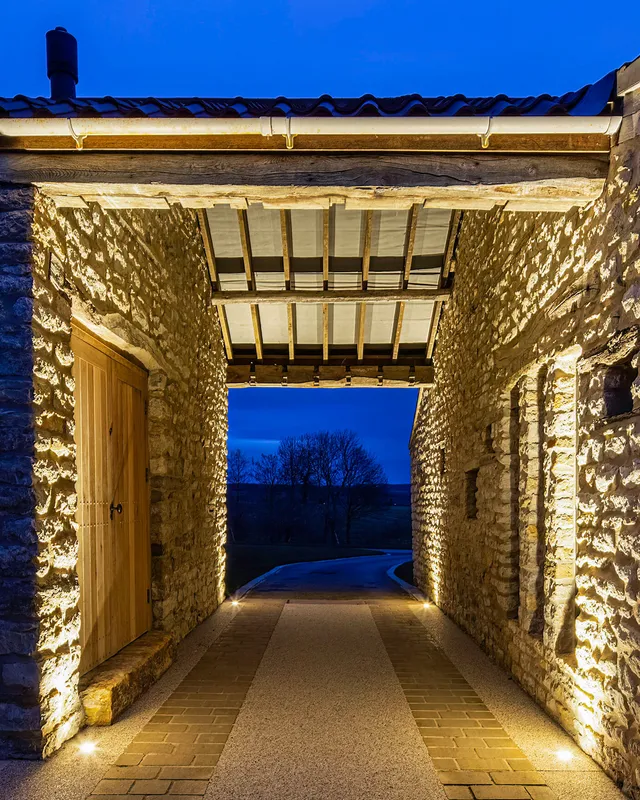 Ground recessed uplights in a stone archway leading to the driveway of a country house