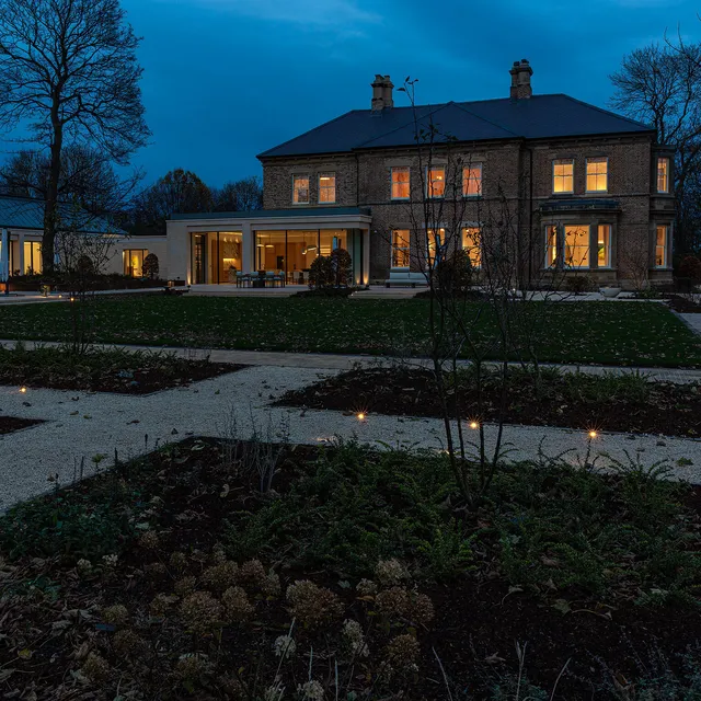 Exterior shot of a Victorian villa with modern kitchen and pool extension in the early evening