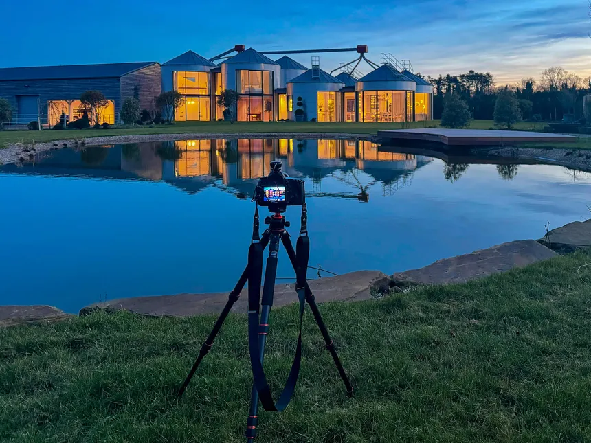 A camera focused on shooting the lighting for The Silos across a lake