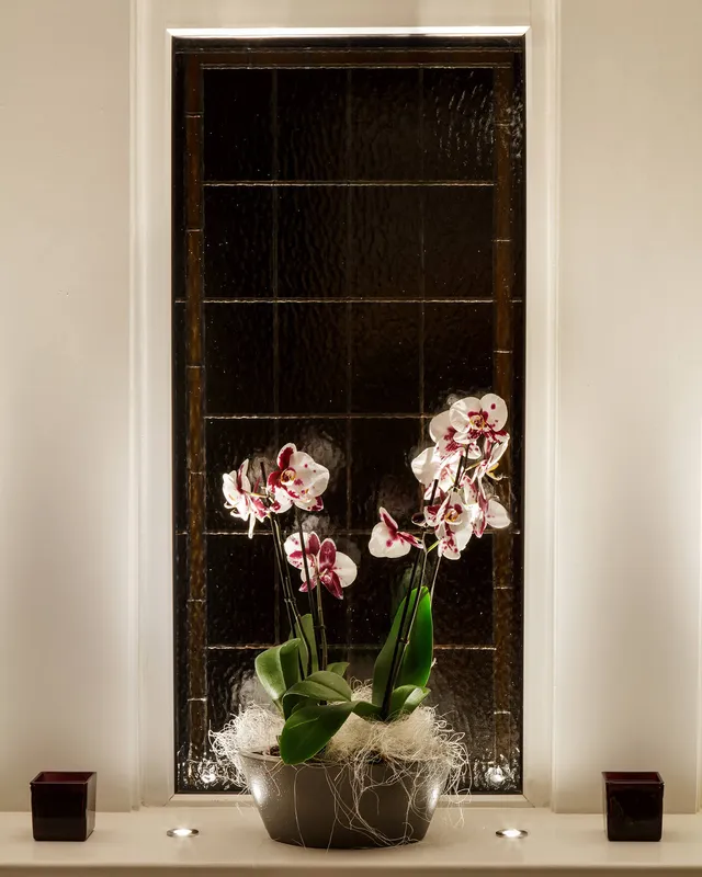 An uplit bowl of lillies in a black and white bathroom 