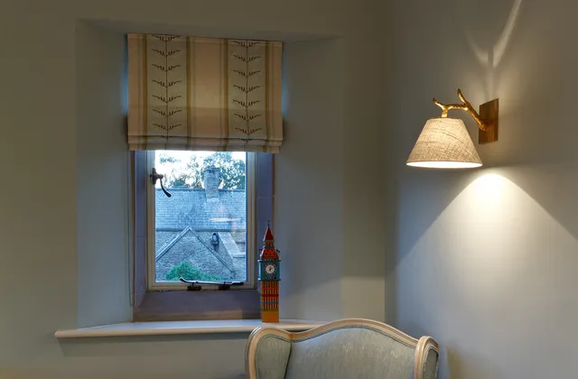 Twig style wall light with fabric lampshade above a reading chair