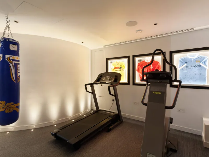 A crisply lit gym with sporting memorabilia, gym machines and an uplit, curved wall.