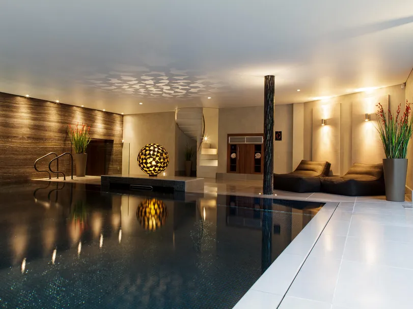 A luxurious swimming pool in a private spa with the pool lighting off and the lighting set to bright