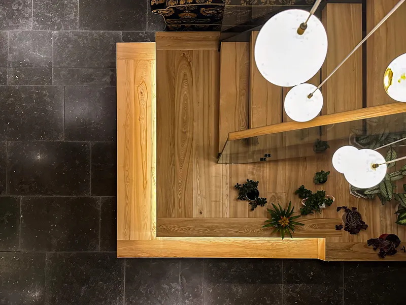 Under-tread looking down on linear LED lighting on a timber, glass and steel staircase