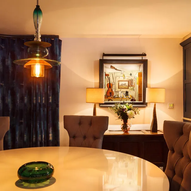 A modern dining room with a decorative pendant and picture lighting