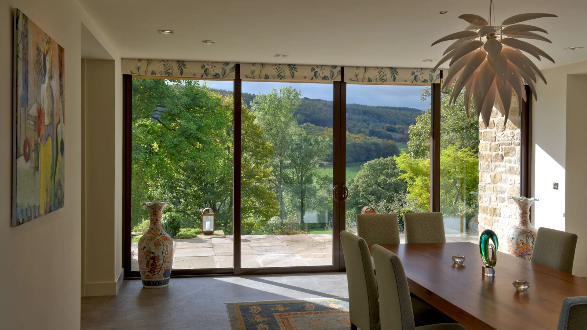 An elegant dining room on a sunny afternoon.  The large galzed doors are shaded with Lutron electric blinds