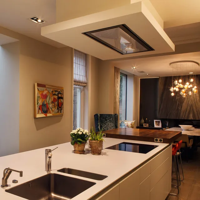 Modern kitchen island looking towards a dining area with lit feature granite fireplace