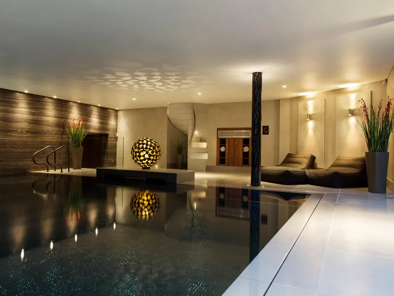 A luxurious swimming pool in a private spa with the pool lighting off and the lighting dimmed