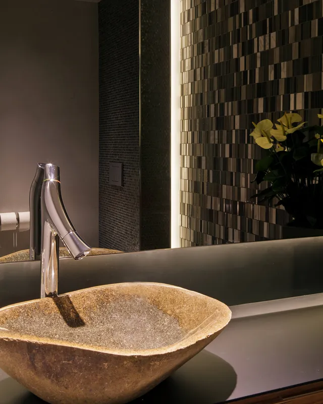 A beautiful stone basin in a moden bathroom with a strip of recessed LED linear lighting