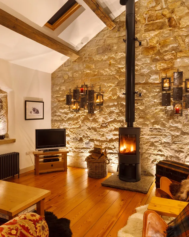 Warm evening lighting with ground-recessed wall uplighting and accent lighting for the feature stone window in a Yorkshire barn