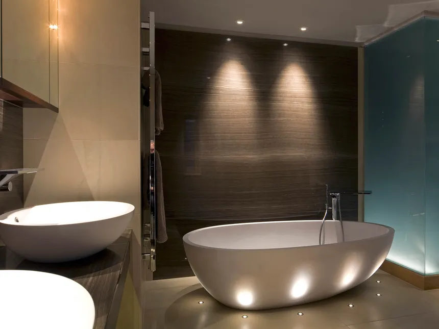 A modern bathroom with an oval freestanding bath uplit with miniature LED accent lights