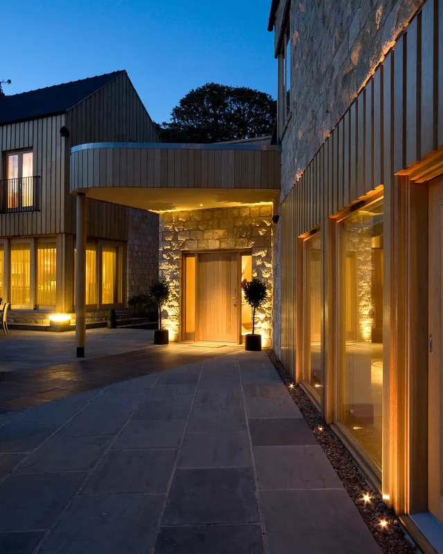 Welcoming eveing lighting for the front of a modern new-build stone house 