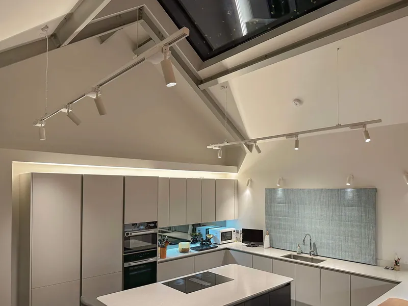 Modern kitchen with pitched glazed ceiling lit with surface and track mounted LED spotlights