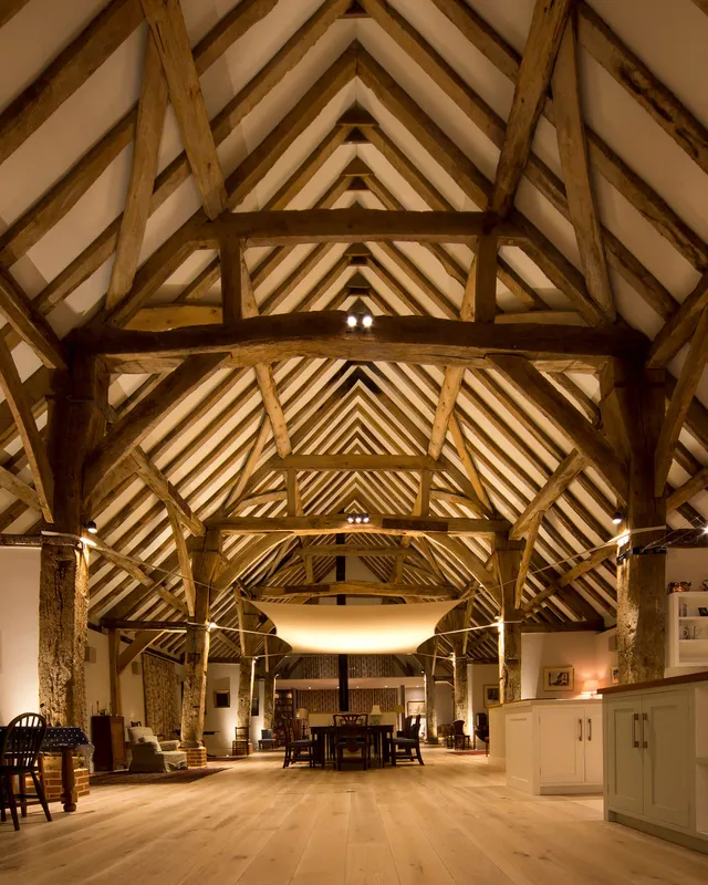 The dining table lit for dinner wtih the sail creating a cosy space in an enormous 16th century Hampshire barn