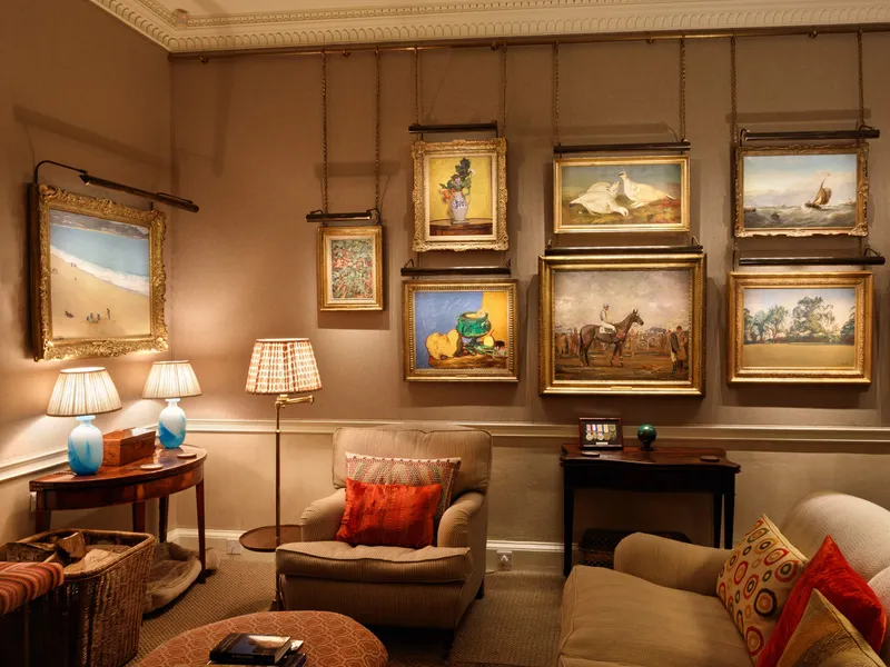 A collection of paintings each individually lit in a comfortable Georgian sitting room