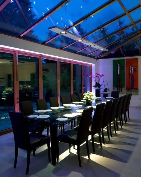 A dining area in an open-plan kitchen dining room with a bespoke LED fitting over the dining table