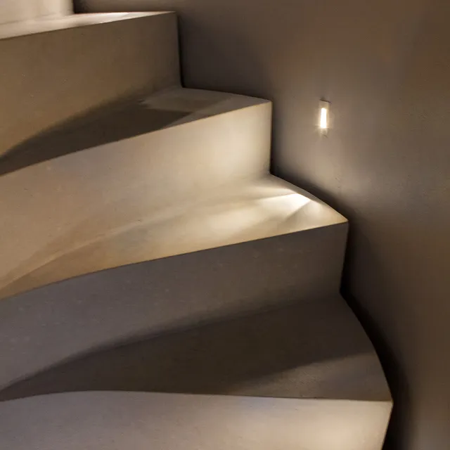 Spiral staircase lit with small, thin wall-mounted accent lights