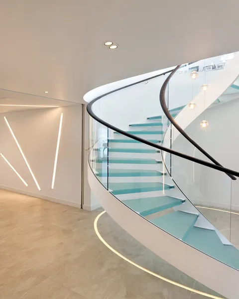 A helical staircase and basement lit with recessed linear LED lighting